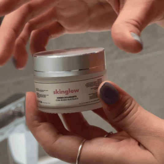 Person holding a jar of 'skinglow' cream with silver lid.
